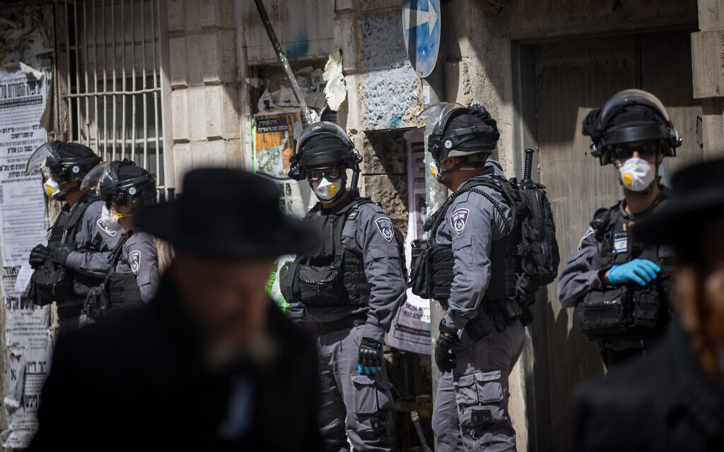 Israeli police officers seen raiding the ultra-Orthodox Jewish neighborhood of Mea Shearim in Jerusalem, closing shops and dispersing public gatherings in an effort to contain the spread of the coronavirus, March 24, 2020. (Yonatan Sindel/Flash90)