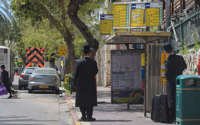 Ultra Orthodox Jewish men wait for a bus in Bnei Brak on March 25, 2020. (Avshalom Sassoni/Flash90)