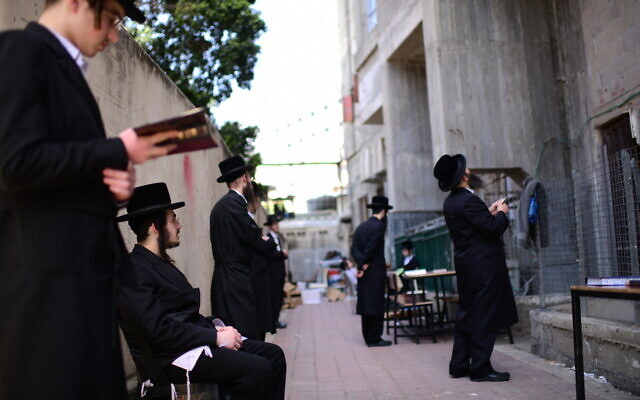 Ultra-Orthodox Jewish men pray outside a closed yeshiva, in the town of Bnei Brak, on March 26, 2020. (Tomer Neuberg/Flash90) Ultra-Orthodox Jewish men pray outside a closed yeshiva, in the town of Bnei Brak, on March 26, 2020. (Tomer Neuberg/Flash90)