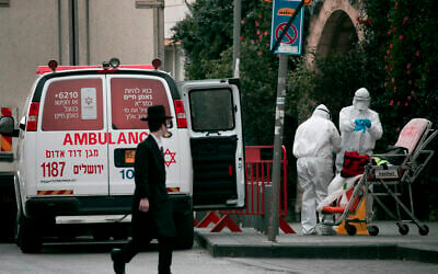 Magen David Adom paramedics, wearing protective clothing as a preventive measure against the coronavirus leave the scene of an emergency call in Jerusalem on March 28, 2020 (Olivier Fitoussi/Flash90) Magen David Adom paramedics, wearing protective clothing as a preventive measure against the coronavirus leave the scene of an emergency call in Jerusalem on March 28, 2020 (Olivier Fitoussi/Flash90)
