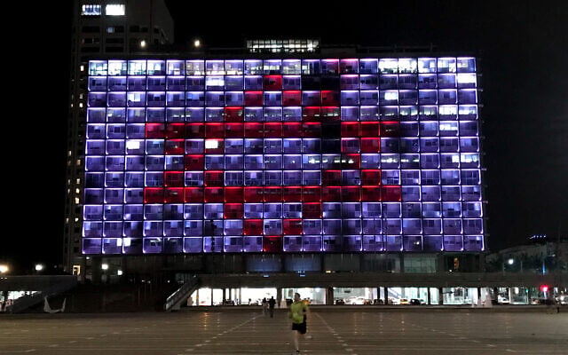Tel Aviv city hall is lit up with the Magen David Adom logo to show support to medical workers battling the coronavirus, March 30, 2020. (Avshalom Sassoni/Flash90) Tel Aviv city hall is lit up with the Magen David Adom logo to show support to medical workers battling the coronavirus, March 30, 2020. (Avshalom Sassoni/Flash90)