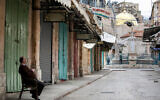 A restaurant owner outside shuttered shops in the Old City of Jerusalem, on March 30 2020. (Olivier Fitoussi/Flash90)