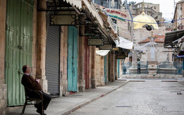 A restaurant owner outside shuttered shops in the Old City of Jerusalem, on March 30 2020. (Olivier Fitoussi/Flash90) A restaurant owner outside shuttered shops in the Old City of Jerusalem, on March 30 2020. (Olivier Fitoussi/Flash90)