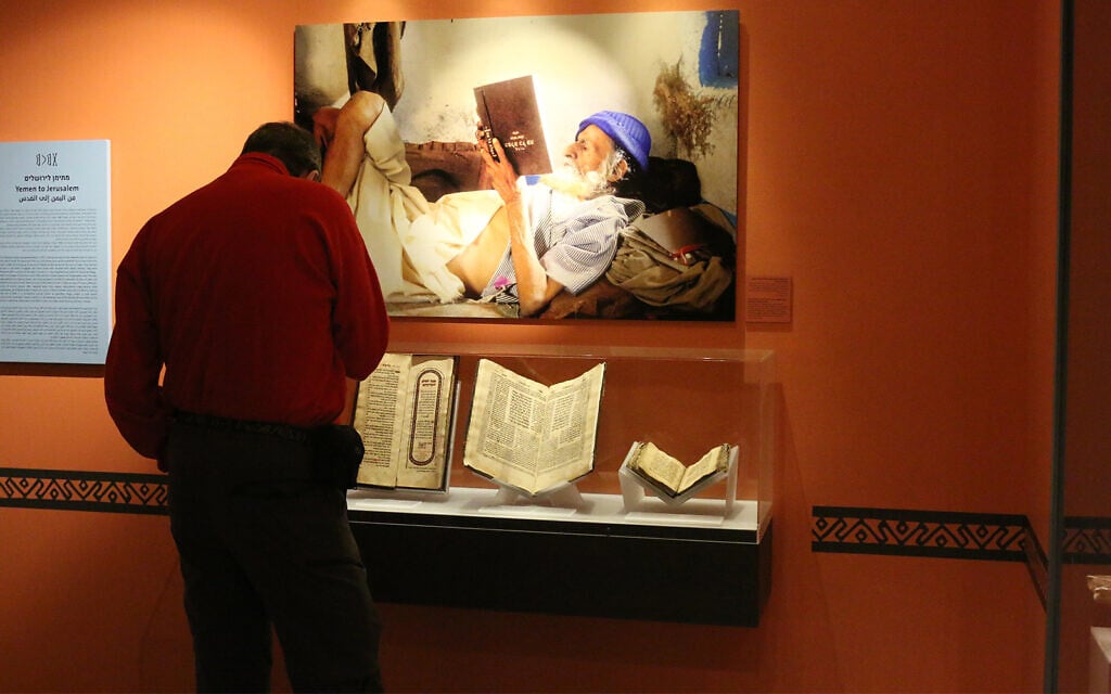 A visitor at the Bible Lands Museum in front of a photo by Naftali Hilger depicting a Yemenite elder reading a book upside down. (Shmuel Bar-Am)