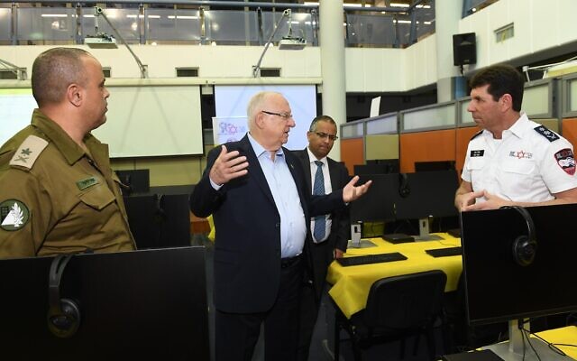 President Reuven Rivlin inaugurates the new national emergency call center jointly run by Magen David Adom (MDA) and the IDF Homefront Command in Ramle as part of the efforts to deal with the coronavirus. At right is Eli Bin, CEO of MDA and left is the IDF Homefront Command's Maj Gen Tamir Yadai. (Mark Neyman) President Reuven Rivlin inaugurates the new national emergency call center jointly run by Magen David Adom (MDA) and the IDF Homefront Command in Ramle as part of the efforts to deal with the coronavirus. At right is Eli Bin, CEO of MDA and left is the IDF Homefront Command's Maj Gen Tamir Yadai. (Mark Neyman)