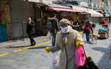 An Israeli woman wearing a face mask for fear of the coronavirus at the Mahane Yehuda Market in Jerusalem, March 22, 2020. (Olivier Fitoussi/Flash90)