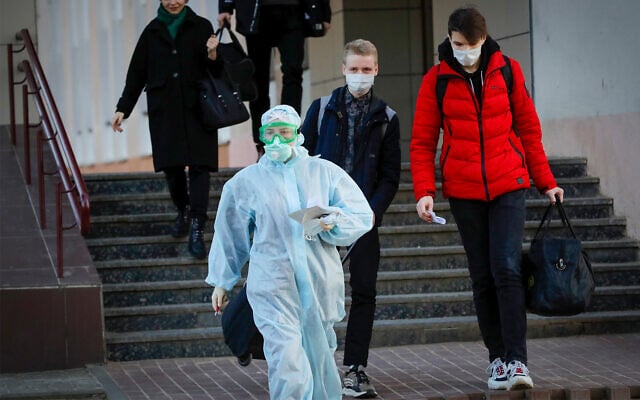 A medical worker wearing a protective suit assists students to an ambulance in Minsk, Belarus, March 13, 2020. (AP Photo/Sergei Grits) A medical worker wearing a protective suit assists students to an ambulance in Minsk, Belarus, March 13, 2020. (AP Photo/Sergei Grits)