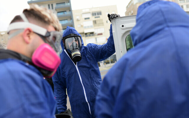 Workers wearing protective clothes disinfect a public playground in Bat Yam as part of measures to prevent the spread of the Coronavirus, March 18, 2020. (Tomer Neuberg/Flash90) Workers wearing protective clothes disinfect a public playground in Bat Yam as part of measures to prevent the spread of the Coronavirus, March 18, 2020. (Tomer Neuberg/Flash90)