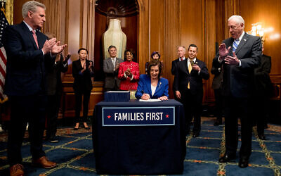 House Speaker Nancy Pelosi of California, accompanied by House Minority Leader Kevin McCarthy of Calif., left, House Majority Leader Steny Hoyer of Maryland right, and other bipartisan legislators, signs the Coronavirus Aid, Relief, and Economic Security (CARES) Act after it passed in the House on Capitol Hill in Washington, DC, March 27, 2020. (AP/Andrew Harnik)
