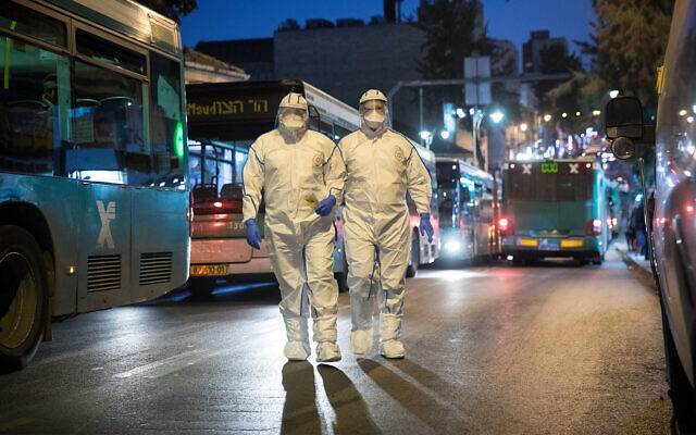 Medical workers wear protective suits as a preventive measure against the coronavirus, as they arrive to test a patient with symptoms, Jerusalem, March 16, 2020. (Yonatan Sindel/ Flash90) Medical workers wear protective suits as a preventive measure against the coronavirus, as they arrive to test a patient with symptoms, Jerusalem, March 16, 2020. (Yonatan Sindel/ Flash90)