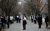 Jewish men use "social distancing" as they pray outside the Chabad Lubavitch World Headquarters in Brooklyn, New York, March 20, 2020. (AP/Mark Lennihan)