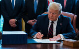 US President Donald Trump signs the coronavirus stimulus relief package in the Oval Office at the White House in Washington, DC, March 27, 2020. (AP/Evan Vucci)