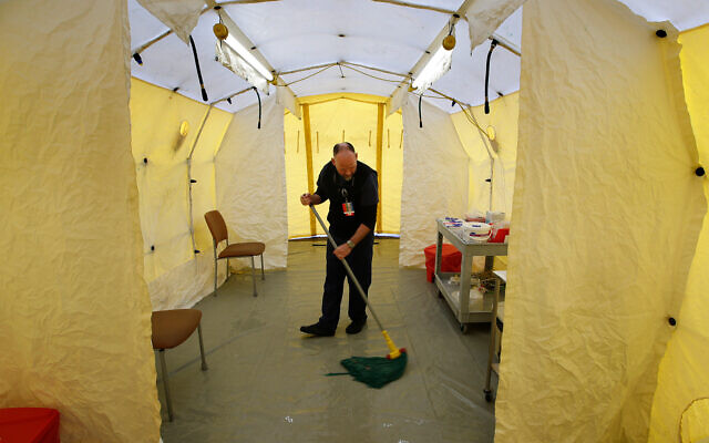 Steve Moody, director of nursing at Central Maine Medical Center in Lewiston, Maine, mops the floor of a tent outside the emergency entrance to the hospital where patients are tested for of the coronavirus, March 13, 2020. (AP/Robert F. Bukaty) Steve Moody, director of nursing at Central Maine Medical Center in Lewiston, Maine, mops the floor of a tent outside the emergency entrance to the hospital where patients are tested for of the coronavirus, March 13, 2020. (AP/Robert F. Bukaty)