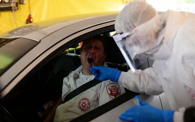 Magen David Adom personnel at a drive-through site to collect samples for coronavirus testing, Tel Aviv, March 20, 2020. (Tomer Neuberg/Flash90)