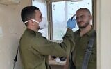 A soldier checks the temperature of a comrade as he enters a military base during the coronavirus pandemic in March 2020. (Israel Defense Forces)