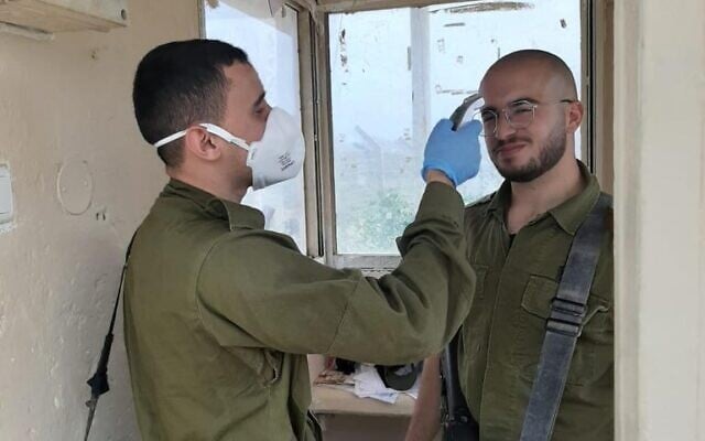 A soldier checks the temperature of a comrade as he enters a military base during the coronavirus pandemic in March 2020. (Israel Defense Forces) A soldier checks the temperature of a comrade as he enters a military base during the coronavirus pandemic in March 2020. (Israel Defense Forces)