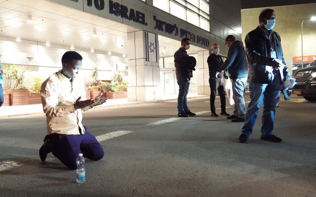 An Ethiopian immigrant kneels on the ground shortly after landing at Ben Gurion Airport, March 24, 2020. (Michael Dimenstein/ GPO)