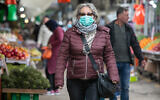 An Israeli woman wears a face mask for fear of the coronavirus while shopping in Ramle, March 19, 2020. (Yossi Aloni/Flash90)