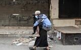 A woman carries a diabled man wearing a protective face mask the Sabra neighbourhood of Beirut where many Palestinian refugees still live on March 22, 2020. (ANWAR AMRO / AFP)