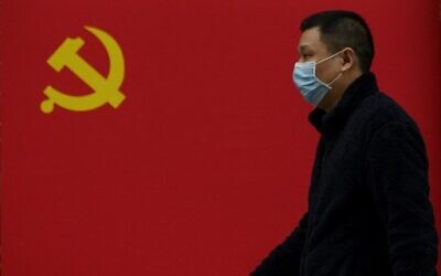A man wearing a face mask as a preventive measure against the coronavirus walks past a Communist Party flag along a street in Wuhan in China's central Hubei province on March 31, 2020. (Noel Celis/AFP) A man wearing a face mask as a preventive measure against the coronavirus walks past a Communist Party flag along a street in Wuhan in China's central Hubei province on March 31, 2020. (Noel Celis/AFP)