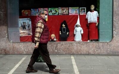 A man walks past a toy shop displaying penitent clothes for children on April 8, 2020, in Seville, Spain, where Easter processions were cancelled during a national lockdown to prevent the spread of the coronavirus disease. (Cristina Quicler/AFP)