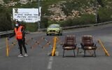 Illustrative: A woman stands next to a makeshift checkpoint in the Druze village of Majdal Shams in the Golan Heights on April 9, 2020. (Jalaa Marey/AFP)
