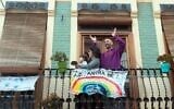 A family applaud from their balcony, adorned with a banner reading 'Everything will be OK,' April 9, 2020, in Valencia, Spain, during a national lockdown to prevent the spread of the coronavirus. (Photo by Jose Jordan / AFP)