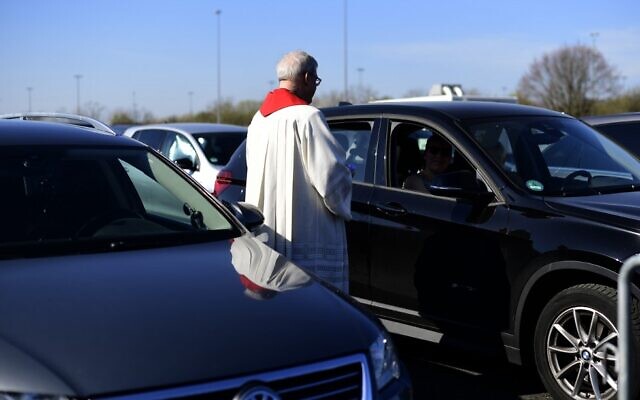 Pastor Frank Heidkamp talks to a visitor in a car during an easter service under the open sky in Duesseldorf drive-in cinema, western Germany, on April 10, 2020, amidst the new coronavirus COVID-19 pandemic. (Ina FASSBENDER / AFP) Pastor Frank Heidkamp talks to a visitor in a car during an easter service under the open sky in Duesseldorf drive-in cinema, western Germany, on April 10, 2020, amidst the new coronavirus COVID-19 pandemic. (Ina FASSBENDER / AFP)