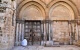 A Christian worshiper prays in front of the closed door of the Church of the Holy Sepulchre in Jerusalem's Old City, before the start of the Easter Sunday service, on April 12, 2020. (Emmanuel Dunand/AFP)