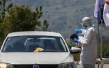 A medical personnel takes a sample from a driver at a Magen David Adom drive-through testing site in the northern city of Kiryat Shmona on April 12, 2020. (Jalaa Marey/AFP)