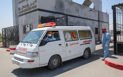 An ambulance drives past a member of security forces loyal to Hamas, the terror group that rules the Gaza Strip, at the Rafah border crossing with Egypt on April 13, 2020. (Said Khatib/AFP)