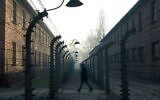 This file photo taken on December 5, 2019, shows a man walking by the barbed wire fence enclosing the memorial site of the former Auschwitz German Nazi death camp. (Janek Skarzynski/AFP)