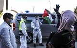 Amir Naji, an 18-year-old Palestinian released by Israel from prison, waves a Palestinian flag while clad in a surgical mask and latex gloves due to the coronavirus pandemic as he is received by his family at a checkpoint near the city of Ramallah in the West Bank on April 14, 2020  (ABBAS MOMANI / AFP)