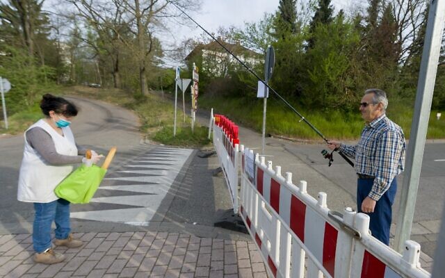 Hartmut Fey, a German citizen of Lauterbach, gets his French baguettes at the German-French border using his fishing rod to avoid a penalty of 250 euros on April 18, 2020, in Carling, eastern France. (Photo by JEAN-CHRISTOPHE VERHAEGEN / AFP) Hartmut Fey, a German citizen of Lauterbach, gets his French baguettes at the German-French border using his fishing rod to avoid a penalty of 250 euros on April 18, 2020, in Carling, eastern France. (Photo by JEAN-CHRISTOPHE VERHAEGEN / AFP)