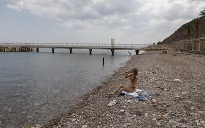 A woman sits along the empty Red Sea shore in the southern resort city of Eilat on April 17, 2020, amid the coronavirus pandemic. (Menahem Kahana/AFP)