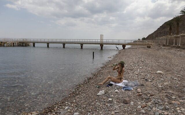 A woman sits along the empty Red Sea shore in the southern resort city of Eilat on April 17, 2020, amid the coronavirus pandemic. (Menahem Kahana/AFP)