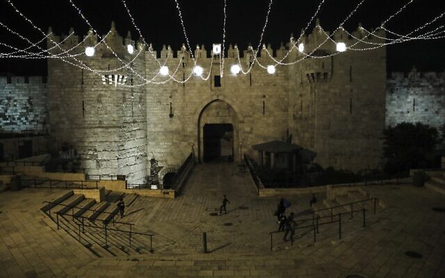 People walk under lights decorating the Damascus Gate in Jerusalem's Old City on April 19, 2020, as Muslims around the world prepare for the holy Muslim month of Ramadan amid the coronavirus pandemic. (Ahmad Gharabli/AFP) People walk under lights decorating the Damascus Gate in Jerusalem's Old City on April 19, 2020, as Muslims around the world prepare for the holy Muslim month of Ramadan amid the coronavirus pandemic. (Ahmad Gharabli/AFP)