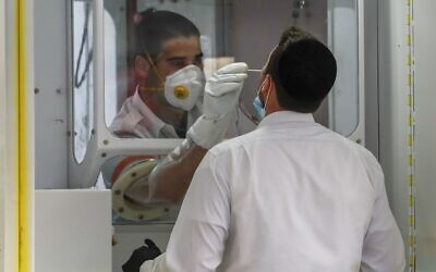 A Magen David Adom paramedic performs a coronavirus test on an ultra-Orthodox Jewish man at a mobile testing station, in Jerusalem's Geula neighborhood, on April 20, 2020. (Ahmad Gharabli/AFP)