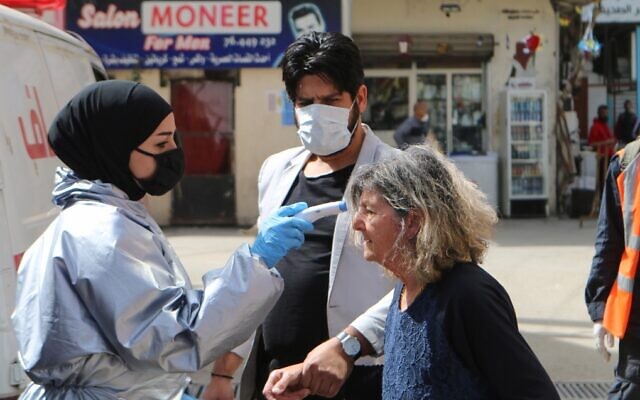 A medic checks the temperature of a woman at the Wavel camp for Palestinian refugees in Lebanon's eastern Bekaa Valley, on April 22, 2020, after the UN announced the first confirmed case of coronavirus there. (AFP) A medic checks the temperature of a woman at the Wavel camp for Palestinian refugees in Lebanon's eastern Bekaa Valley, on April 22, 2020, after the UN announced the first confirmed case of coronavirus there. (AFP)
