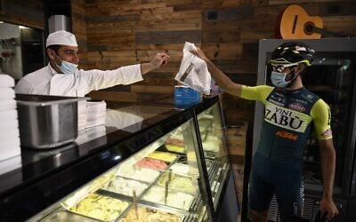 Vini Zabu - KTM rider Umberto Marengo (R) picks a bag of ice creams at a shop during a day of delivery on April 22, 2020 in Collegno, near Turin (MARCO BERTORELLO / AFP)