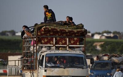 Illustrative: Displaced Syrians ride in the back of a truck towards the Deir al-Ballut checkpoint to return to their villages in Afrin's countryside in the northern Syrian province of Aleppo, along the border with Turkey, on April 22, 2020. (Rami al Sayed/AFP)
