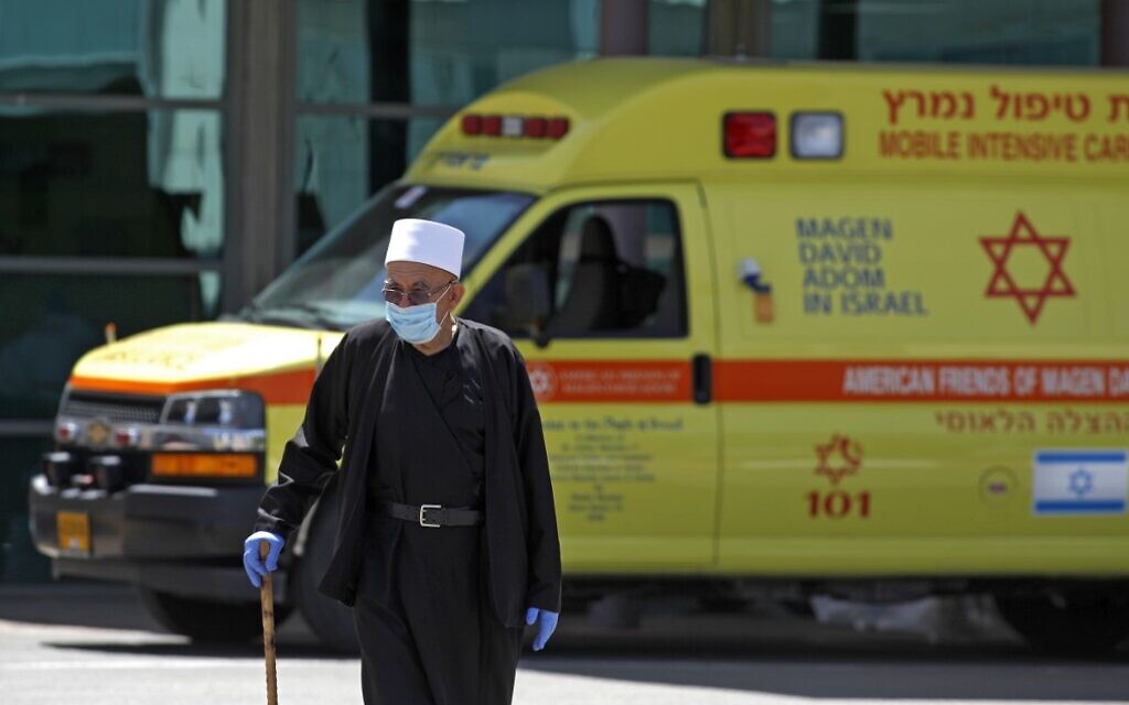 Illustrative: A Druze man wearing a surgical mask walks past an ambulance outside Ziv Medical Center in the northern city of Safed on April 23, 2020. (Jalaa Marey/AFP) Illustrative: A Druze man wearing a surgical mask walks past an ambulance outside Ziv Medical Center in the northern city of Safed on April 23, 2020. (Jalaa Marey/AFP)
