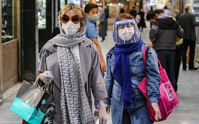 Shoppers clad in protective gear, including face masks and shields and latex gloves, due to the COVID-19 pandemic, walk through the Tajrish Bazaar in Iran's capital Tehran on April 25, 2020, during the Muslim holy month of Ramadan. (ATTA KENARE / AFP) Shoppers clad in protective gear, including face masks and shields and latex gloves, due to the COVID-19 pandemic, walk through the Tajrish Bazaar in Iran's capital Tehran on April 25, 2020, during the Muslim holy month of Ramadan. (ATTA KENARE / AFP)