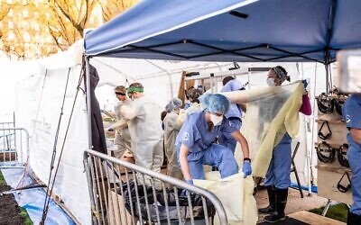 Medical workers putting on protective gear at the beginning of their shift at the emergency field hospital run by Samaritan's Purse and Mount Sinai Health System in Central Park on April 8, 2020 in New York. (Misha Friedman/Getty Images/AFP)