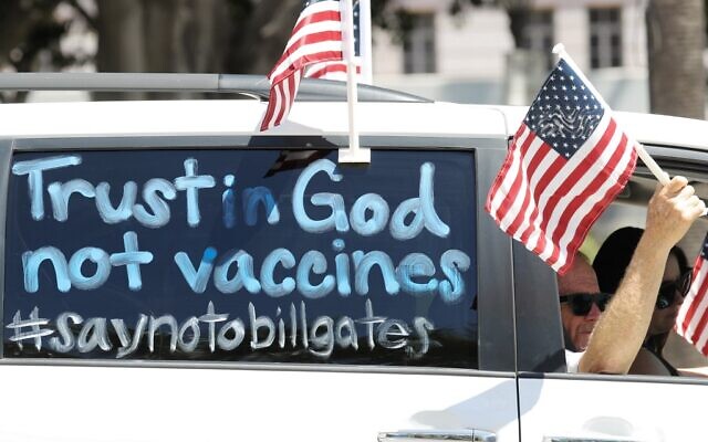 Demonstrators participate in a vehicle caravan with a sign reading 'Trust in God not vaccines' outside City Hall, on April 22, 2020, in Los Angeles, California. (Mario Tama/Getty Images/AFP) Demonstrators participate in a vehicle caravan with a sign reading 'Trust in God not vaccines' outside City Hall, on April 22, 2020, in Los Angeles, California. (Mario Tama/Getty Images/AFP)