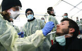 German medical employees demonstrate testing at a coronavirus test center for public service employees, during a media presentation in Munich, Germany, March 23, 2020. (AP Photo/Matthias Schrader, File)