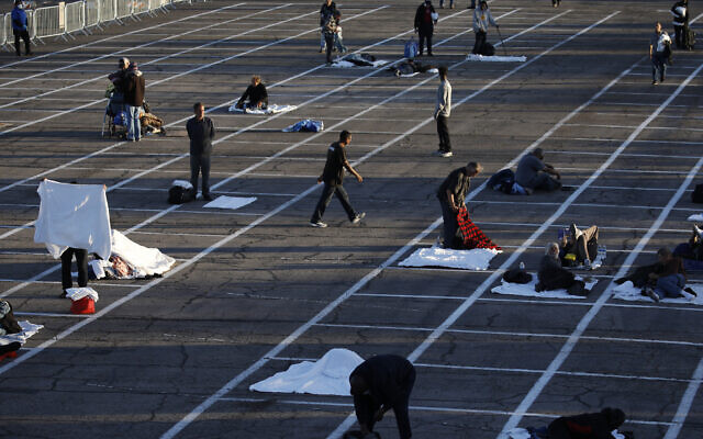 People prepare to sleep in areas marked by painted boxes on the ground of a parking lot at a makeshift camp for the homeless Monday, March 30, 2020, in Las Vegas. Officials opened part of the ot as a makeshift homeless shelter after a local shelter closed when a man staying there tested positive for the coronavirus. (AP Photo/John Locher) People prepare to sleep in areas marked by painted boxes on the ground of a parking lot at a makeshift camp for the homeless Monday, March 30, 2020, in Las Vegas. Officials opened part of the ot as a makeshift homeless shelter after a local shelter closed when a man staying there tested positive for the coronavirus. (AP Photo/John Locher)