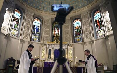 The Rev. Steven Paulikas, right, and curate Spencer Cantrell deliver an Evening Prayer service over Facebook Live in the Brooklyn borough of New York, March 29, 2020. (AP Photo/Emily Leshner)