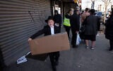 An boy carries a box of matzah for Passover that he picked up from his synagogue in the Brooklyn borough of New York, on March 26, 2020. (AP Photo/Mark Lennihan)