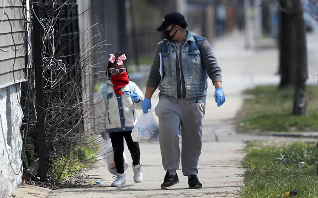In this April 7, 2020 photo, Erica Harris, right, and her daughter Jordan, wear their protective masks as they walk back home after getting a lunch and homework from the child’s school on Chicago’s Southside in Chicago (AP Photo/Charles Rex Arbogast) In this April 7, 2020 photo, Erica Harris, right, and her daughter Jordan, wear their protective masks as they walk back home after getting a lunch and homework from the child’s school on Chicago’s Southside in Chicago (AP Photo/Charles Rex Arbogast)